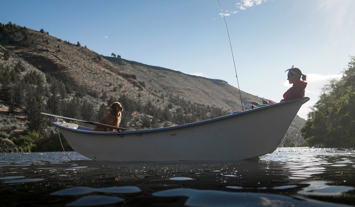Chimmy and Linsey sit in opposite ends of a fishing boat on the river.
