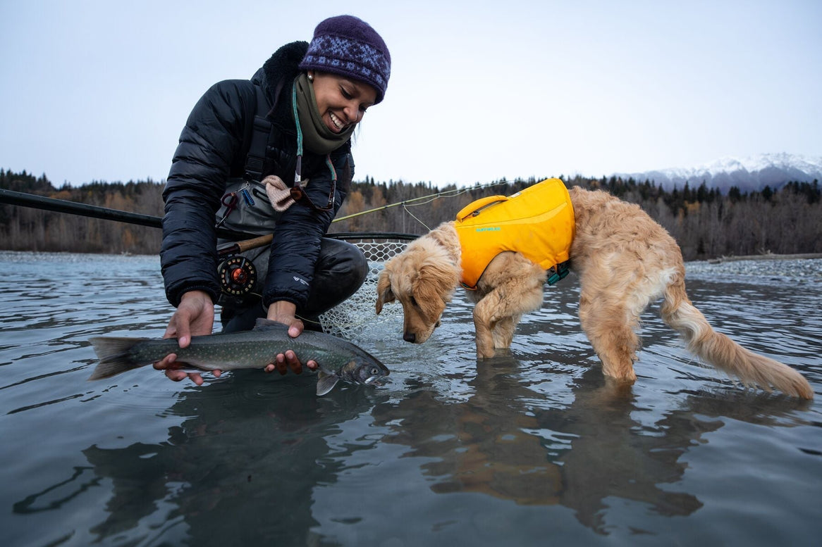 Chris holds up a fish above the water and Sammy checks it out.