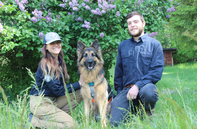 Hugo, a Rogue Detection Dog, poses with his two family members.