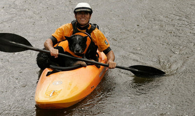 Founder Patrick Kruse in kayak with his dog in a float coat sitting in his lap.