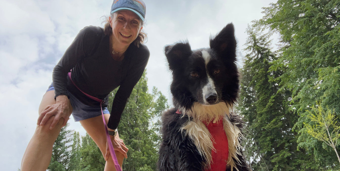 A woman and her dog smile at the camera on a break from running. 