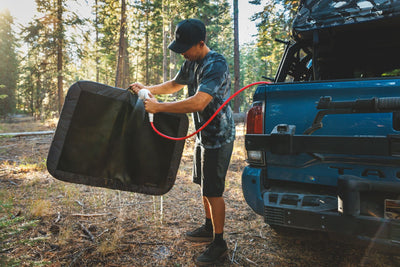 A man washes off his Dirtbag™ Bed with a hose.