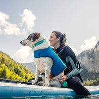Woman sitting on a paddleboard with her dog.