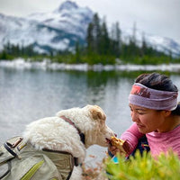 Cassie eats a snack out of Theresa's hands by alpine lake.