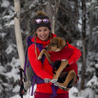 Caroline holds her dog Lila in the snowy woods.