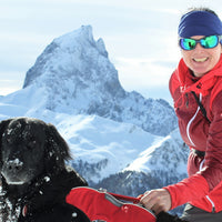 Caroline and her dog Fjord sit atop a snowy ridge in the Alps.
